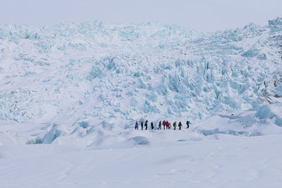 People on glacier against sky