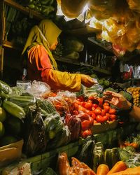 Mature woman selling various vegetables at market