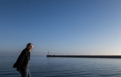 Adult man against sea and sky with lighthouse in background. almeria, spain