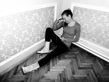 Full length of young woman sitting against wall