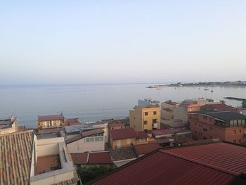 High angle view of buildings by sea against clear sky