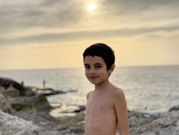 Portrait of shirtless boy at beach against sky