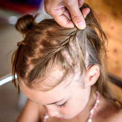 Cropped hands of mother braiding daughter hair