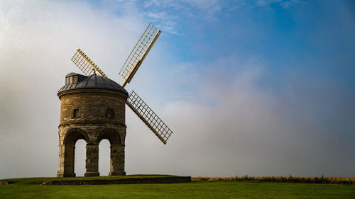 Traditional windmill on field against sky