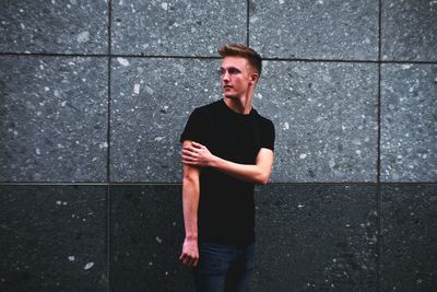 Young man standing against wall