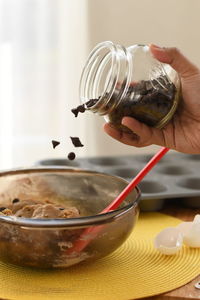 Cropped hand pouring chocolate chips in bowl