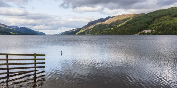 Scenic view of lake by mountains against sky