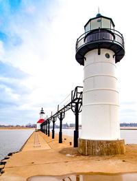 Lighthouse by sea against sky