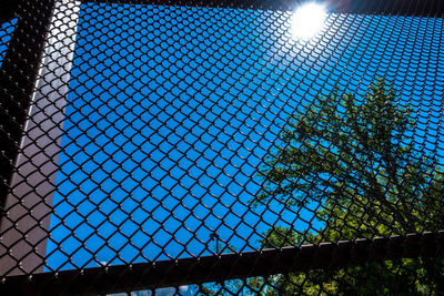 Low angle view of chainlink fence against blue sky