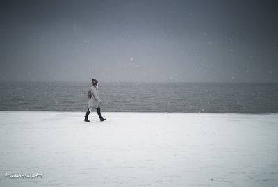 Full length of woman standing on beach against sky during winter