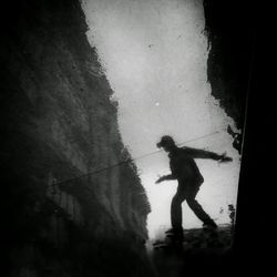 Silhouette man standing by water against sky