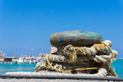 Close-up of rope tied to boat moored at harbor against clear blue sky