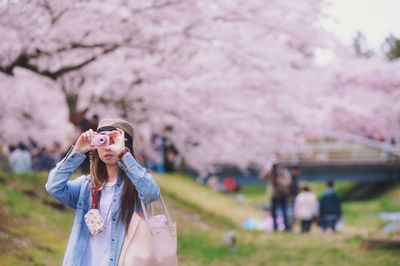 Young woman with flowers on tree against blurred background