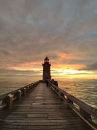 Pier over sea against sky during sunset