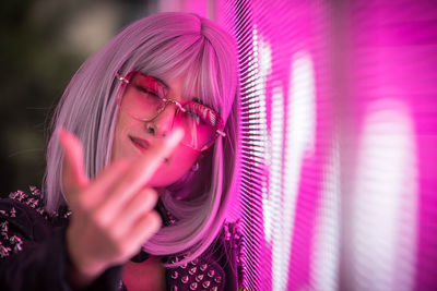 Portrait of young woman gesturing while standing against abstract backgrounds