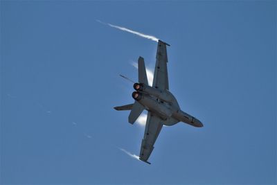 Low angle view of airplane flying against clear blue sky