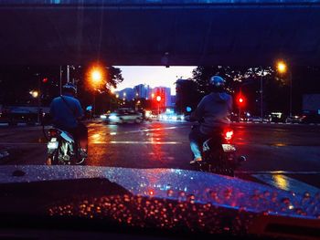 Rear view of people walking on wet street at night