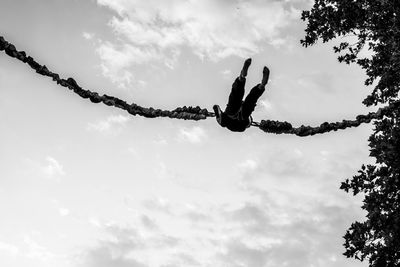 Low angle view of people on rope against sky