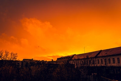 Silhouette buildings against orange sky