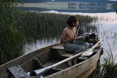 Man sitting by lake against plants