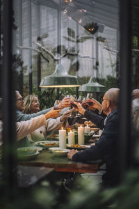 Male and female friends toasting drinks during dinner party in backyard