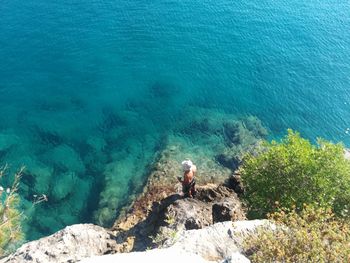 High angle view of man sitting on rock by sea