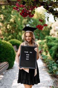 Portrait of young woman holding blackboard