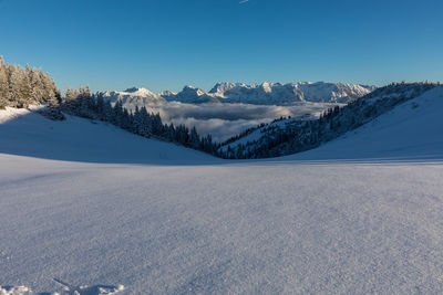 Scenic view of snow covered mountains against blue sky