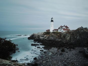 Lighthouse by sea against sky