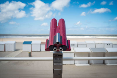 Close-up of coin-operated binoculars by sea against sky