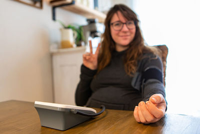 Portrait of smiling woman checking blood pressure at home