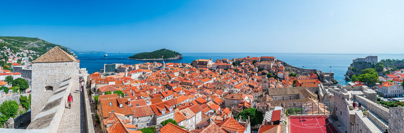 High angle view of townscape by sea against clear blue sky