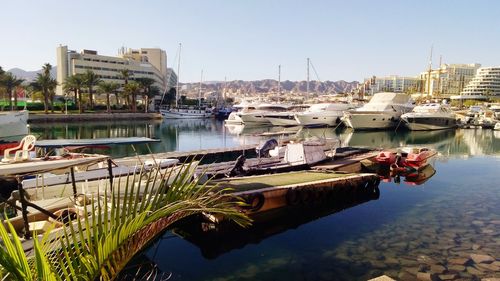 Boats moored at harbor against buildings in city