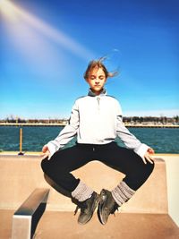 Portrait of young woman sitting on retaining wall