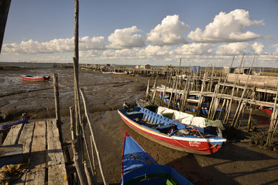 Boats moored at harbor against sky