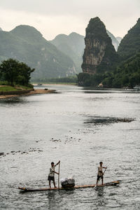 Men on wooden raft sailing in river