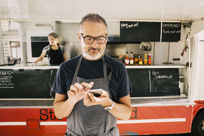 Owner using mobile phone against street food truck