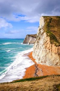 Scenic view of beach against cloudy sky