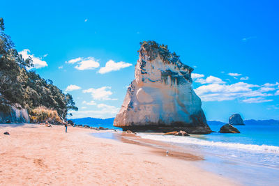 Rock formations on beach against blue sky