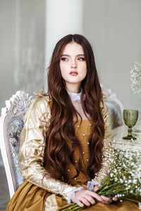 Portrait of a girl in a gloden dress with long brown hair