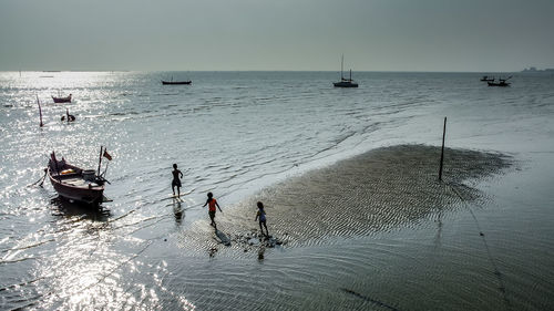 High angle view of children walking towards boats at beach