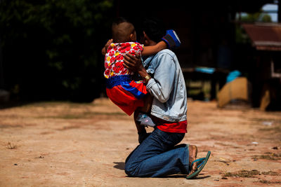 Side view of father holding girl with son