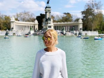 Portrait of young woman standing against lake