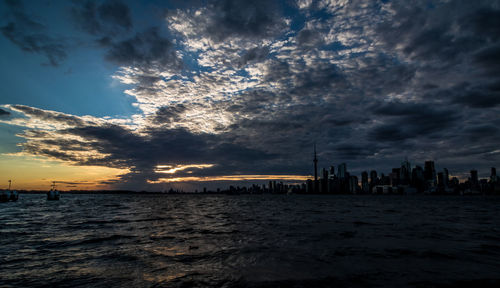 Scenic view of sea by buildings against sky during sunset