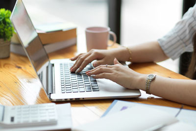 Midsection of woman using laptop on table