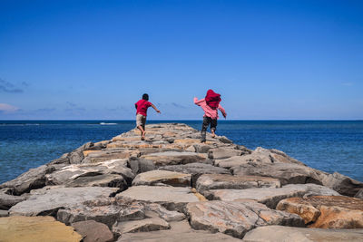 Siblings running on grayon at beach