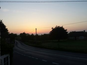 Electricity pylons on road at sunset