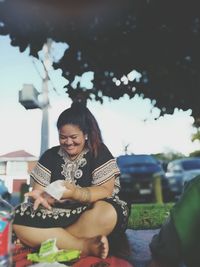 Full length of smiling overweight woman sitting outdoors