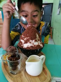 Close-up of boy with ice cream in plate on table