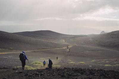 Rear view of people walking on mountain against sky